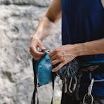 Man adjusting climbing gear with harness outdoors on a sunny day.